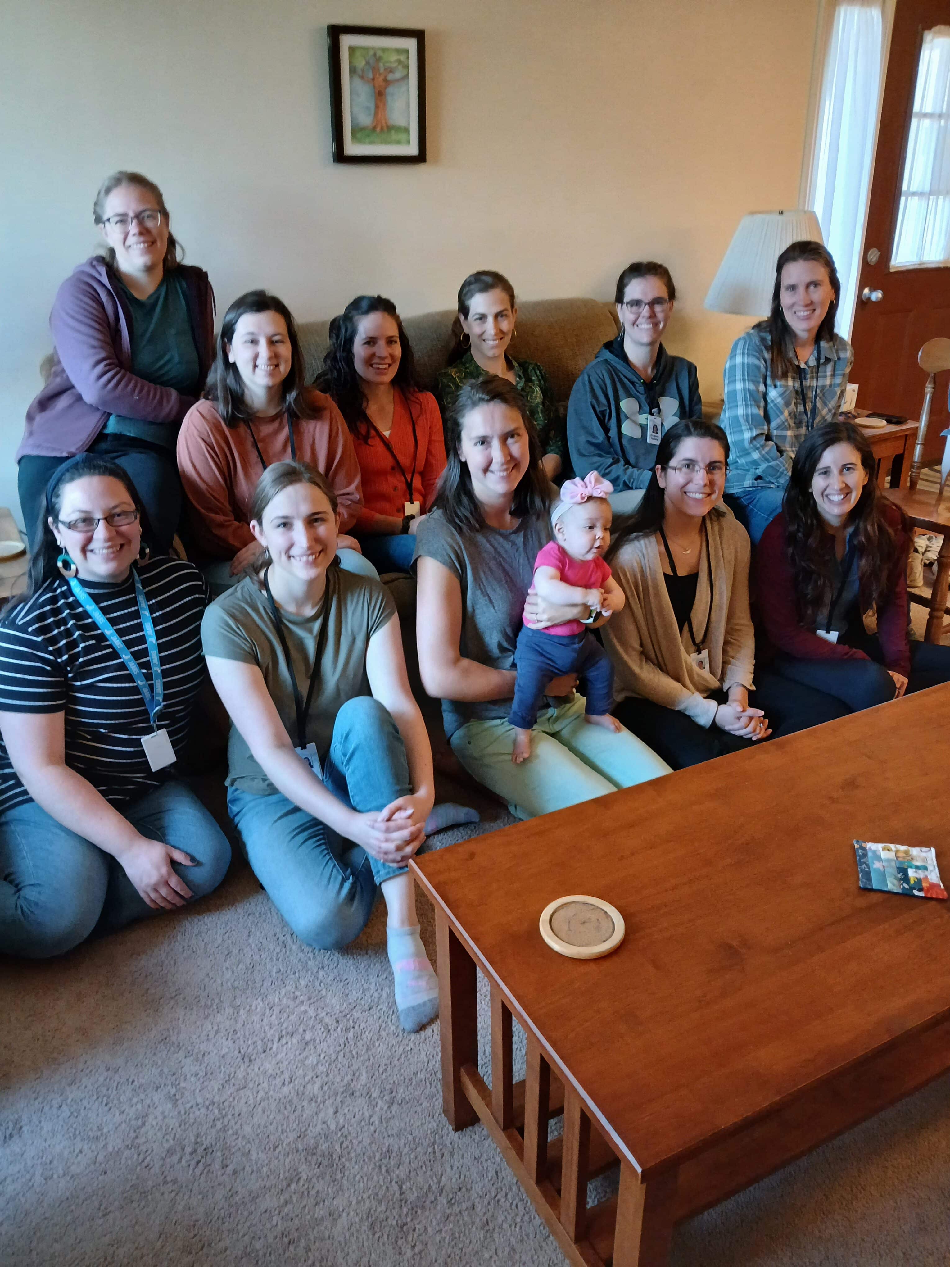 A group of women sitting in a living room and smiling for the camera.